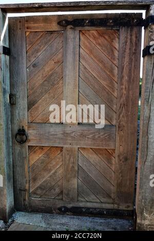 Rustic old wooden gate in brick wall. Old wooden door in UK. Stock Photo