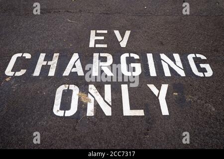 EV charging only in white on the pavement of an electric vehicle charging space Stock Photo