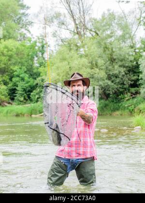 Fishermans Landing. mature man fly fishing. man catching fish. fisherman show fishing technique use rod. hobby and sport activity. Happy bearded fisher in water. summer weekend. Fly fishing. Stock Photo