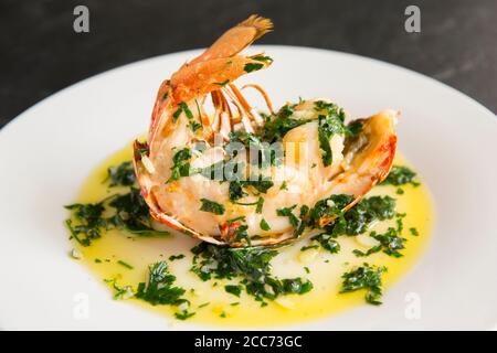 A half lobster tail, Homarus gammarus, that has been grilled and drizzled with a butter, garlic and parsley sauce. The lobster was caught in the Engli Stock Photo