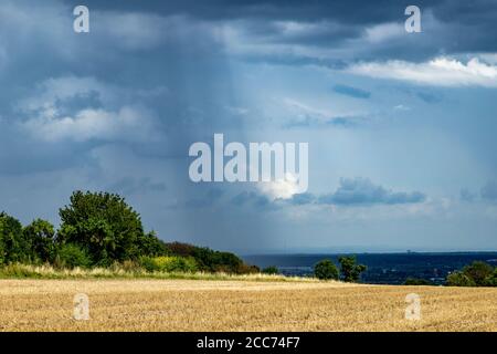 rain falls in streaks from a cloud in countryside area, field in the foreground, weather Stock Photo