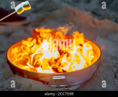 marsh mellows on a stick over a small fire on the beach in Montauk, NY Stock Photo