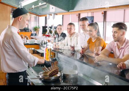 The chef prepares food in front of the visitors in the restaurant Stock Photo