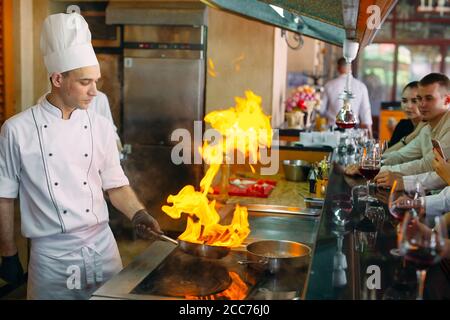 The chef prepares food in front of the visitors in the restaurant The chef prepares food in front of the visitors in the restaurant