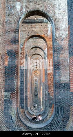 Young people under the Ouse Valley Viaduct (Balcombe Viaduct) carrying the London to Brighton Railway Line over the River Ouse in Sussex, UK Stock Photo