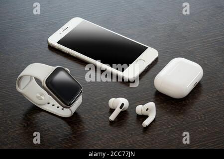 Izmir, Turkey - August 7, 2020: Close up shot of white colored Iphone 8, Apple Watch 5, and Air Pods pro on a wooden ground. Stock Photo