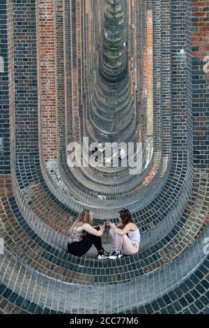 Young people under the Ouse Valley Viaduct (Balcombe Viaduct) carrying the London to Brighton Railway Line over the River Ouse in Sussex, UK Stock Photo