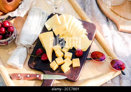 French style romantic picnic setting. Set of cheese, cherry. Blanket with food prepared for summer picnic Stock Photo