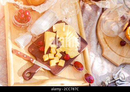 French style romantic picnic setting. Set of cheese, orange juice, bun, cherry. Blanket with food prepared for summer picnic Stock Photo