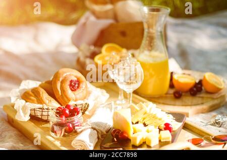 Blanket with food prepared for summer picnic at the park. Cheese, fruits, breads, juice and snacks on blanket Stock Photo