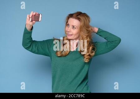 Caucasian mature woman take a self portrait with her smart phone. Stock Photo