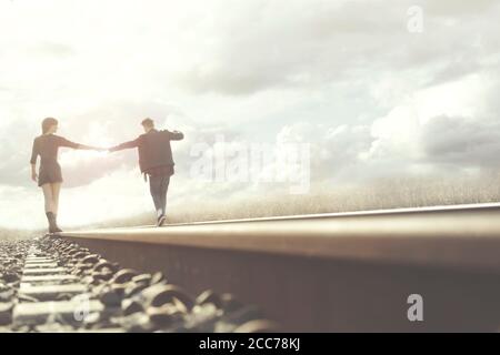 young couple walks hand in hand on rails in a surreal place Stock Photo