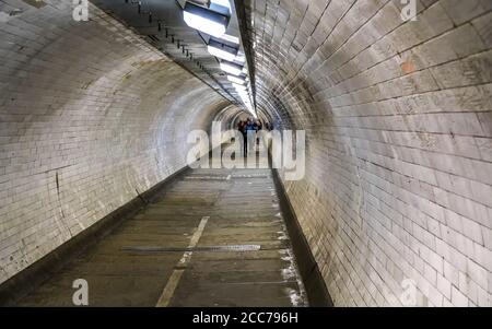 Wide angle photo of Greenwich foot tunnel under river Thames in London, blurred pedestrians in distance Stock Photo