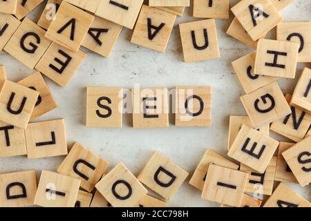 Top down view, pile of square wooden blocks with letters SEO (stands for Search Engine Optimization) on white board. Stock Photo