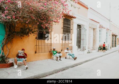 Men relaxing in chairs on the sidewalk of a local street in Cartagena Stock Photo