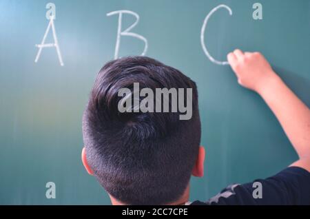 student writes letters on the board, concept for education Stock Photo