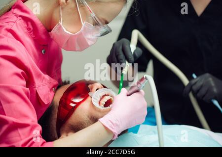 Professional teeth cleaning. Dentist cleans the teeth of a male patient. Stock Photo