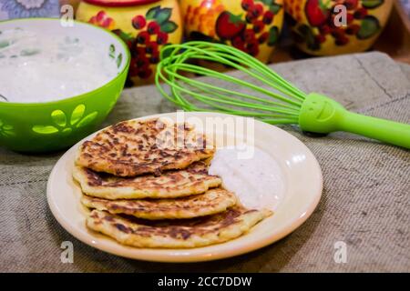 Zucchini pancakes with sauce from sour cream Stock Photo