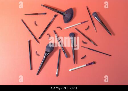 Orange surface on which there are different makeup brushes and false eyelashes for professional use Stock Photo