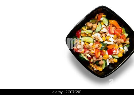 Tasty vegetable salad with chicken close up in a black bowl Isolated on white background Stock Photo