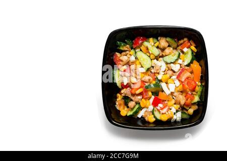 Tasty vegetable salad with chicken in a black plate Isolated on white background. Place for text Stock Photo