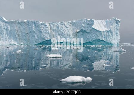 A massive tabular iceberg and its reflection in calm glassy water in Antarctica. Stock Photo