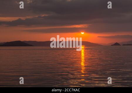 The sun sets over the flores sea in Komodo National park, Indonesia. Stock Photo