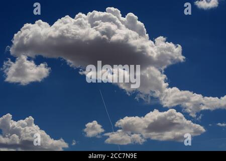 A jet airplane leaves a long contrail as it flies high over the American Southwest. Stock Photo