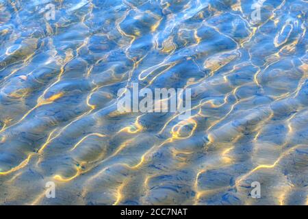 Sunlit ripple marks in shallow water. The bright ripples are caused sun light bent by small waves. Stock Photo