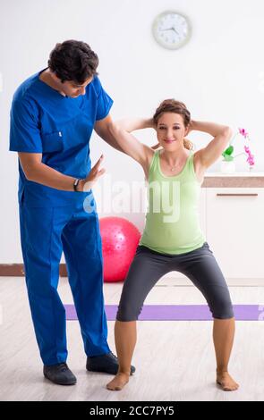 The pregnant woman doing physical exercies with instructor Stock Photo