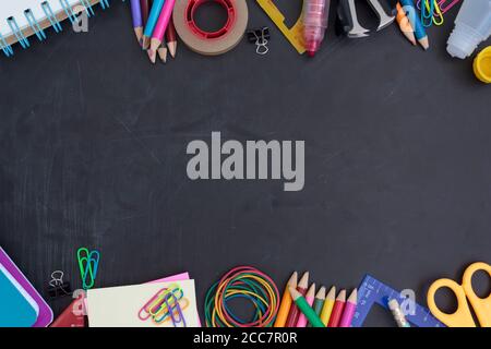 School supplies on chalkboard with copy space in the middle. Back to school concept Stock Photo