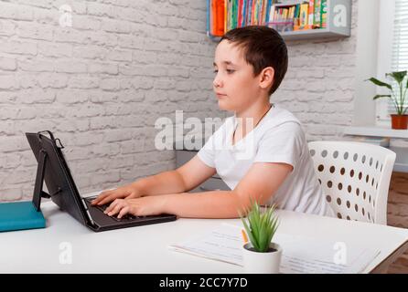 Cheerful schoolkid writing in notebook and smiling at camera Stock Photo