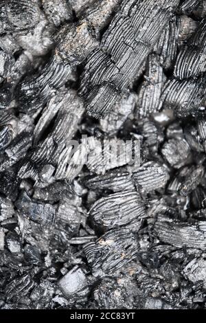 Soft focus to black gray background of charcoal pieces cooling down into barbecue mangal. Selective focus to wooden coals and embers texture Stock Photo