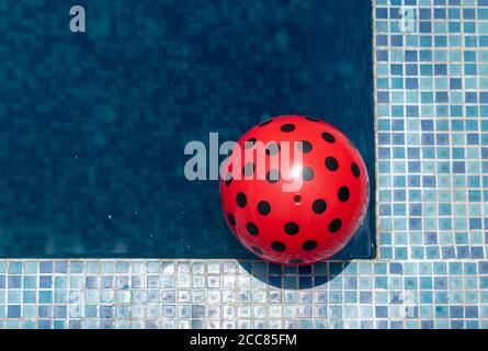 Top view of a red ball floating on the corner of a swimming pool on a sunny day. Stock Photo