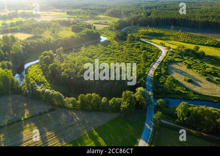 Latvian rural landscape with a winding river, forests and country roads at sunset, aerial top view Stock Photo