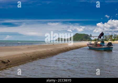 This unique photo shows a fishing boat running aground on the beach in Thailand and the Pak Nam Pran mountain range in the background Stock Photo