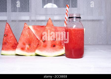 Watermelon smoothie and slices of fresh red watermelon on white wooden table background. copy space Stock Photo