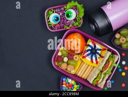 Halloween lunch box with school lunch with sandwich and vegetable salad on black background Stock Photo