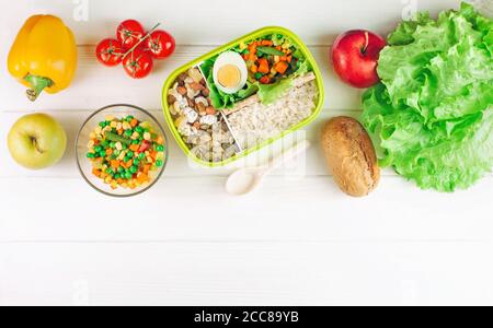 Lunch box filled with rice and mixed vegetables on white wooden background Stock Photo