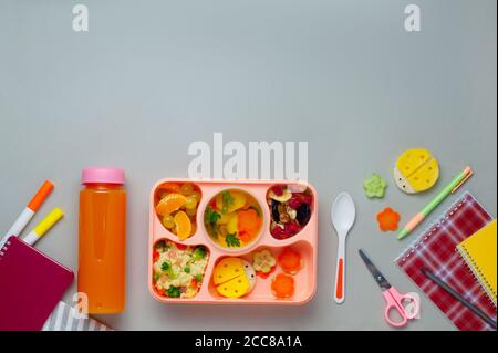 Lunch box with orange juice and notebooks on grey background Stock Photo