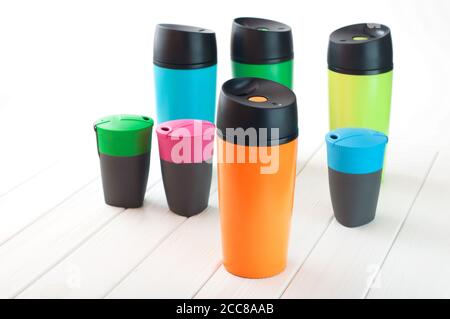 Many modern color thermos mugs on white wooden background Stock Photo