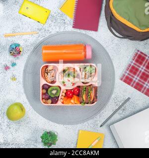 Open lunch box with healthy food on the grey background with school backpack Stock Photo