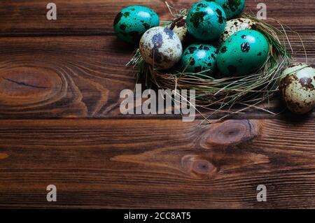 Painted quail eggs in nest over rustic wooden background Stock Photo