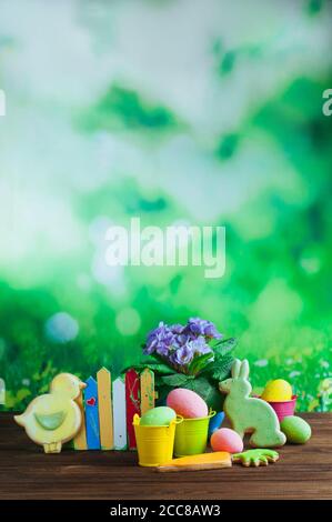 Painted eggs, Easter gingerbreads and primrose flower on wooden background Stock Photo