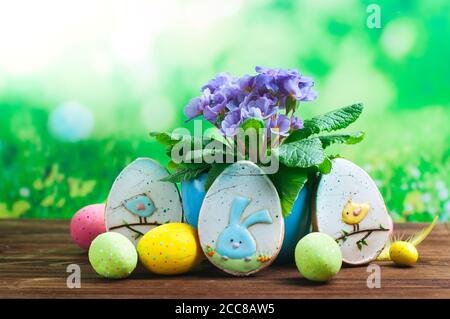 Painted eggs, Easter gingerbreads and primrose flower on wooden background Stock Photo