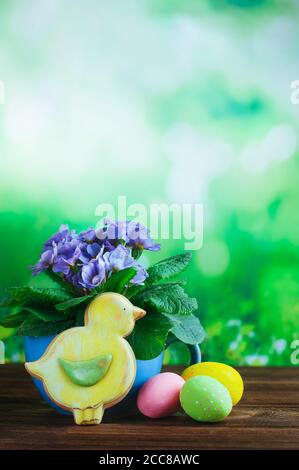 Painted eggs in small buckets, Easter bird gingerbread and primrose flower on rustic wooden background Stock Photo