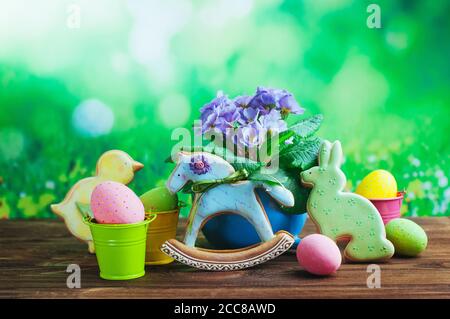 Painted eggs, Easter gingerbreads and primrose flower on wooden background Stock Photo