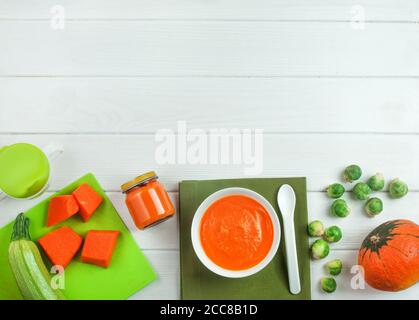 Puree from pumpkin in the plate and jar on white wooden background Stock Photo