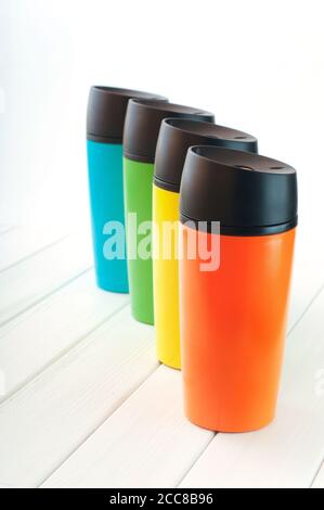 Series of color thermos mugs on the white wooden table Stock Photo