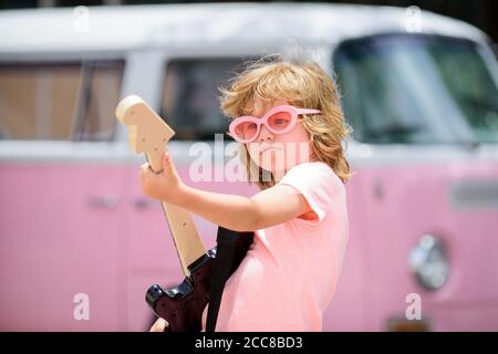 Happy smiling child learning to play the guitar. Retro colorful kids portrait. Future rock star. Stock Photo